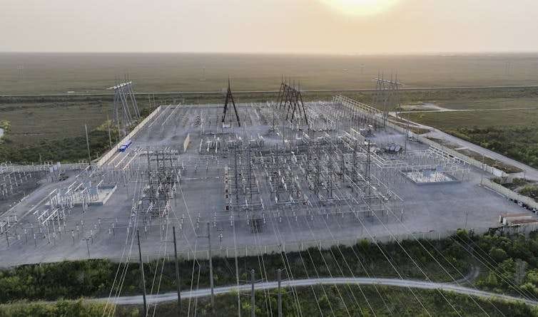 An aerial view of an area covered in wires, metal boxes and towers.