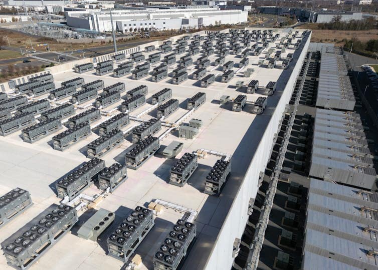 Rows of small equipment boxes sit atop the roof of a commercial building.